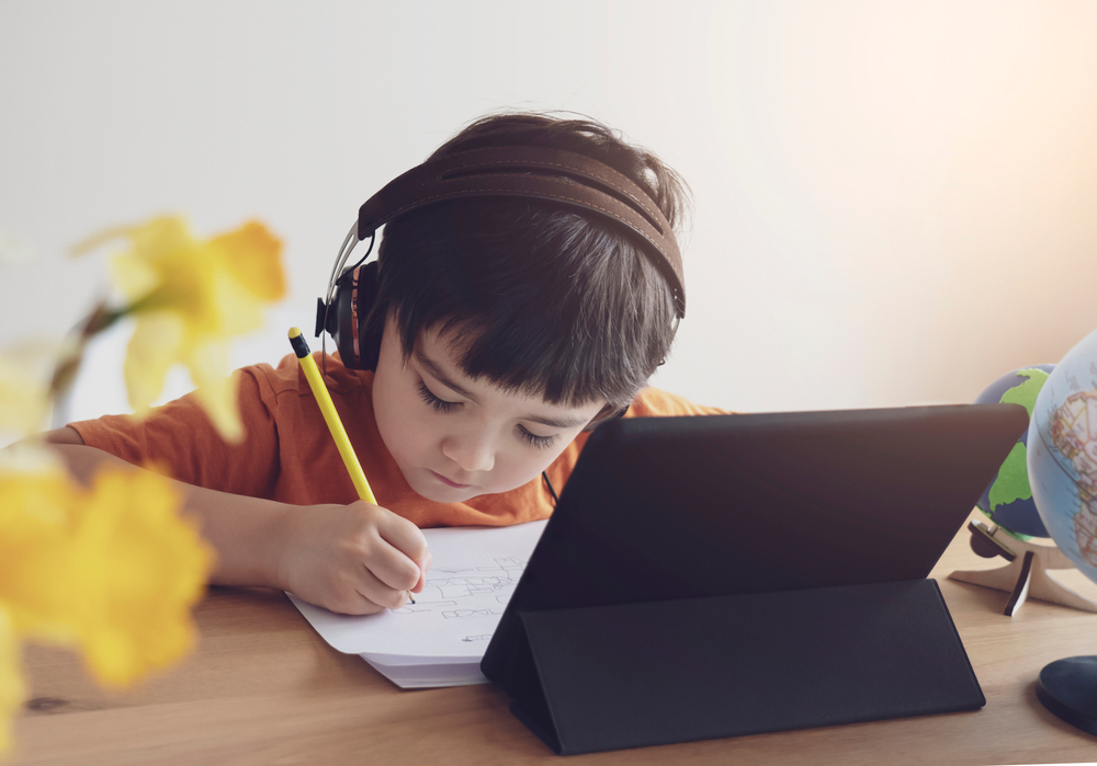 Boy with headphones using a reading and writing app to aid his learning process