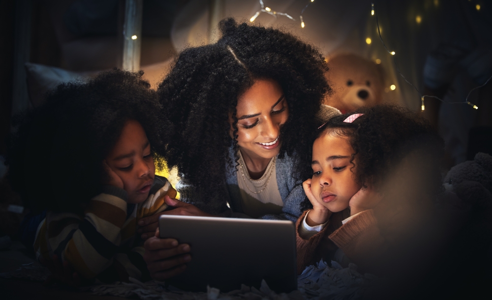 Mother and children enjoy a digital daily routine reading session before bedtime, highlighting family bonding and technology in learning