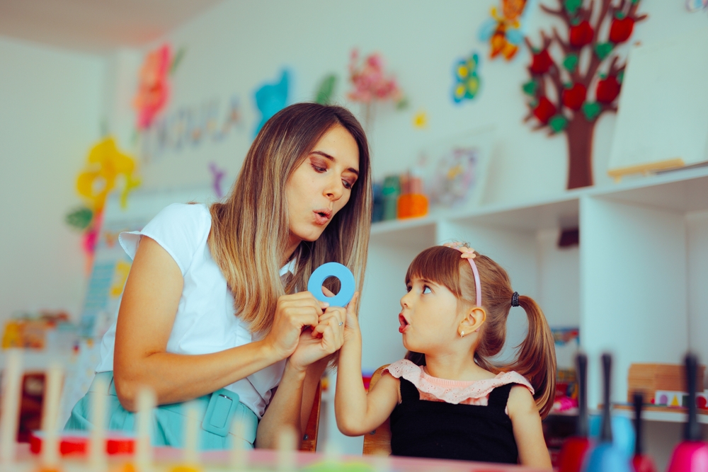 Teacher interacting with child, identifying signs of childhood dyslexia