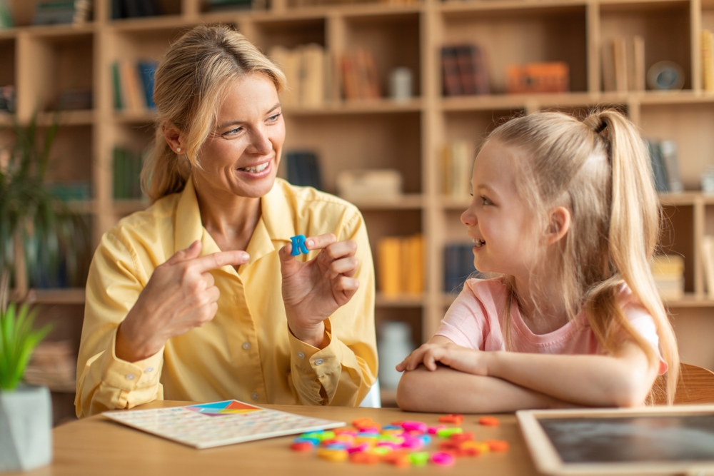Teacher helping a child with dyslexia using alphabet pieces
