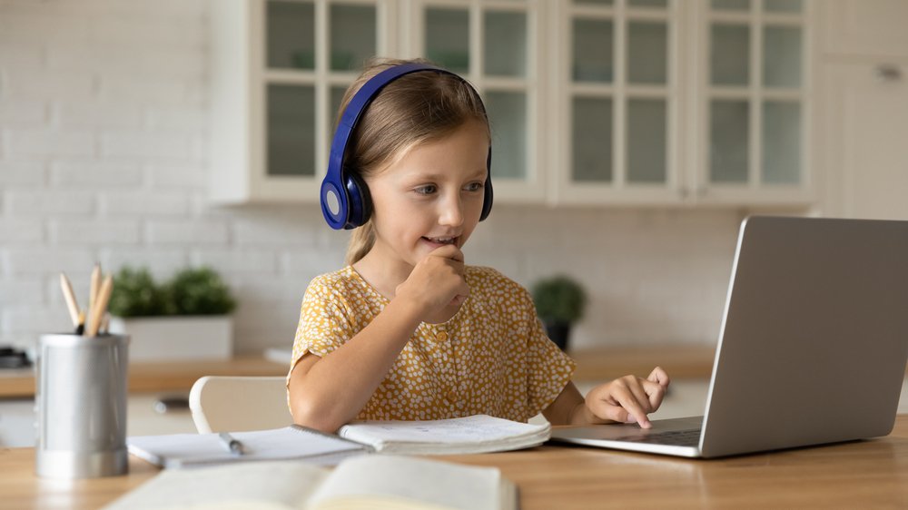 Girl engaged in listening and reading comprehension activities with laptop and headphones