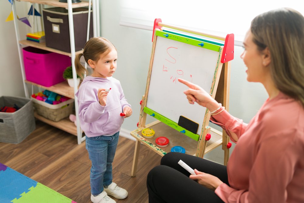 Child with autism learning to write letters with help from an educator
