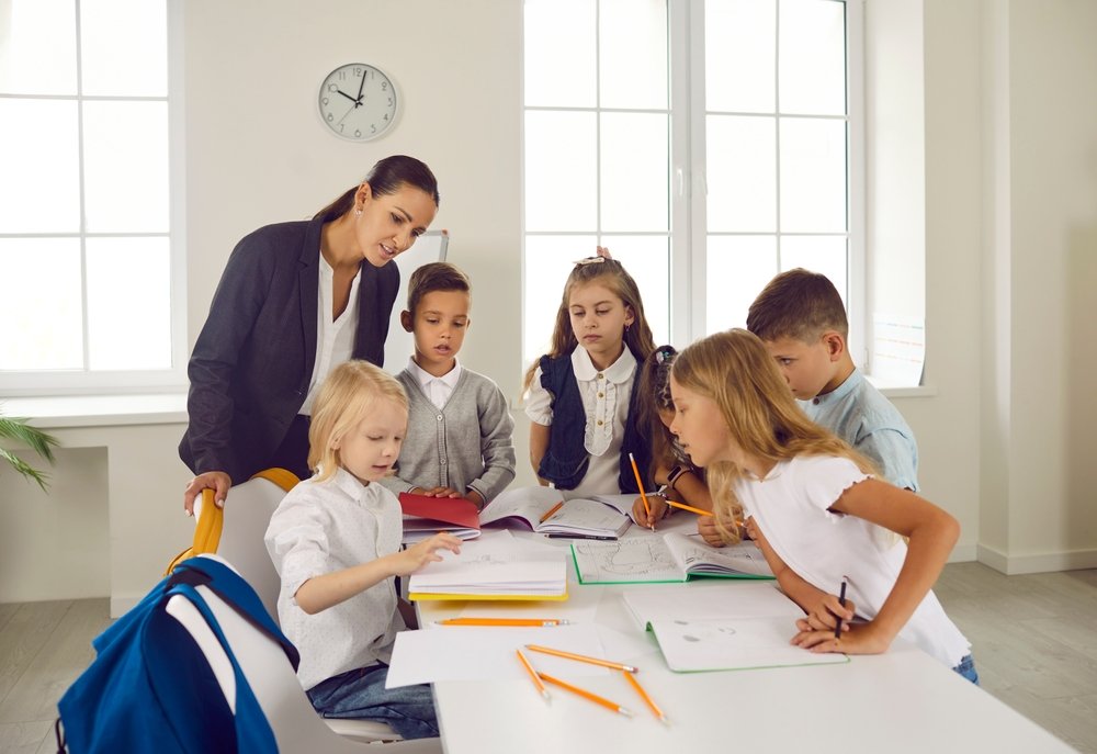 Teacher assisting kids with interactive reading activities for critical thinking
