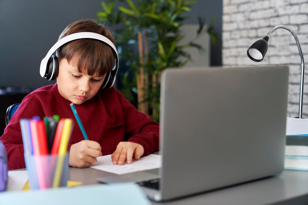 a boy wearing headphones and writing on paper