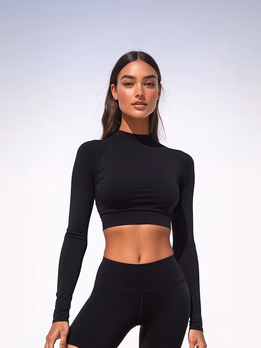 Fit woman in black long-sleeve crop top and high-waisted biker shorts against a light background.