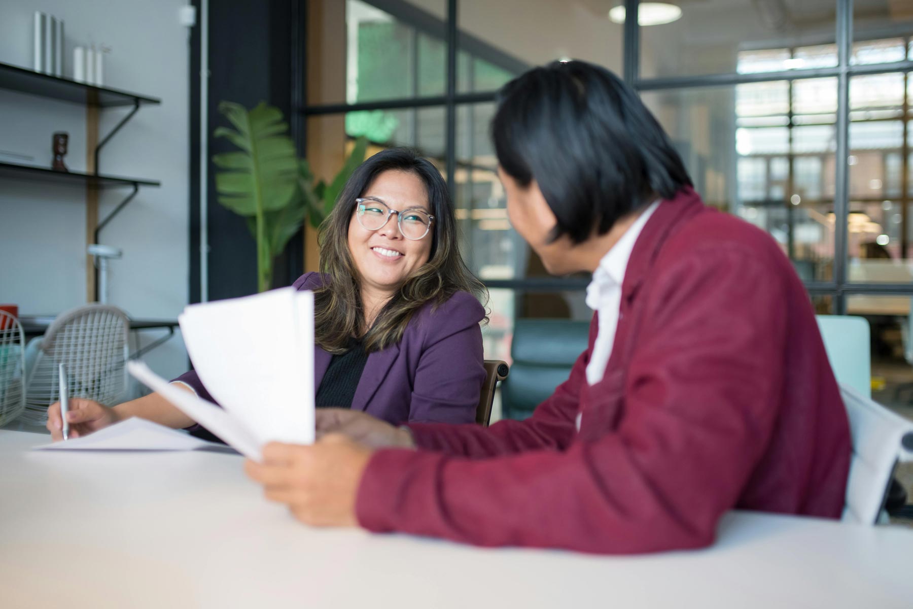 Office meeting with two colleagues smiling and holding paper