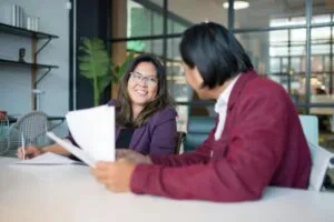 Office meeting with two colleagues smiling and holding paper