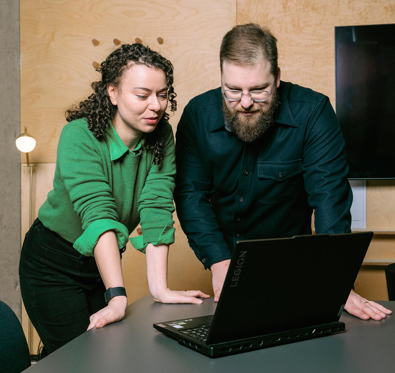 Emma Anderson Beavers and Miroslav Kriz leaning over a table, collaborating while looking at a laptop screen
