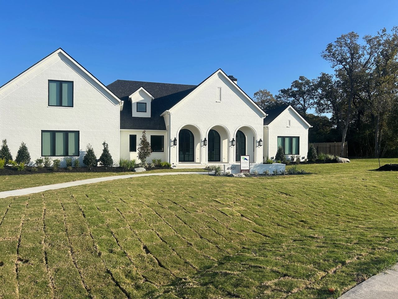 Side view of large stone home with multiple roof pitches and new shingles in Southlake TX