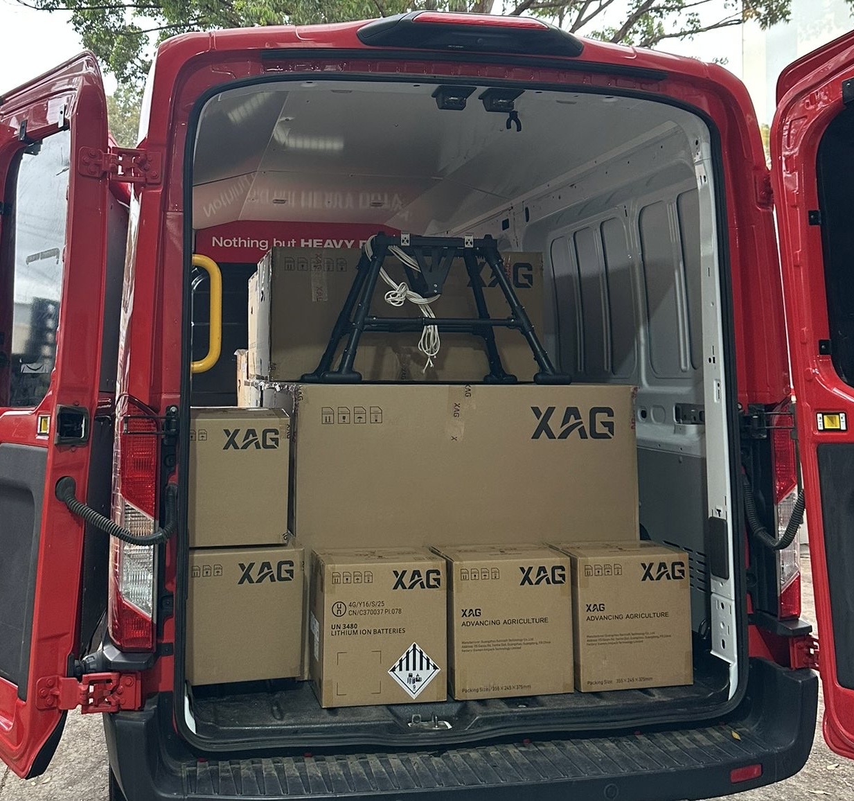 Worker in safety harness sealing a shingled roof with a caulking gun under a clear blue sky.