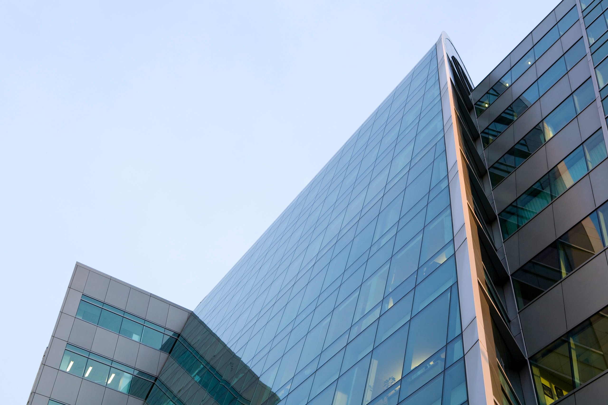 Upward view of modern glass and steel office buildings against clear sky.