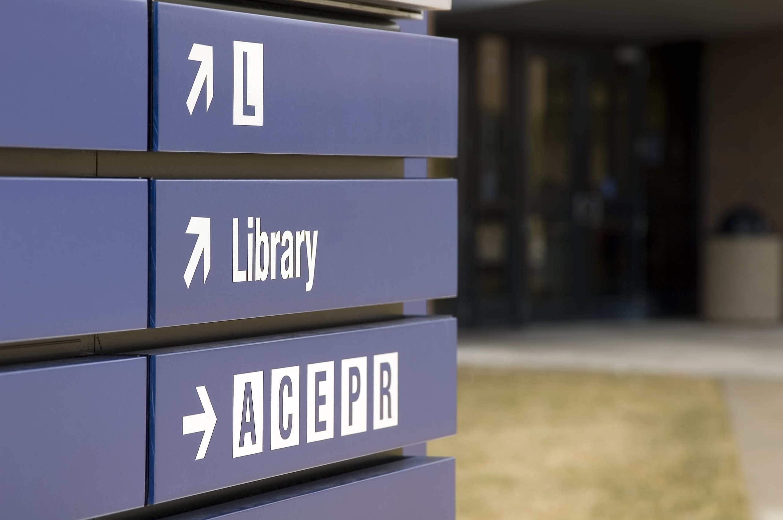 Blue directional sign pointing to the library and areas labeled A, C, E, P, R with arrows.