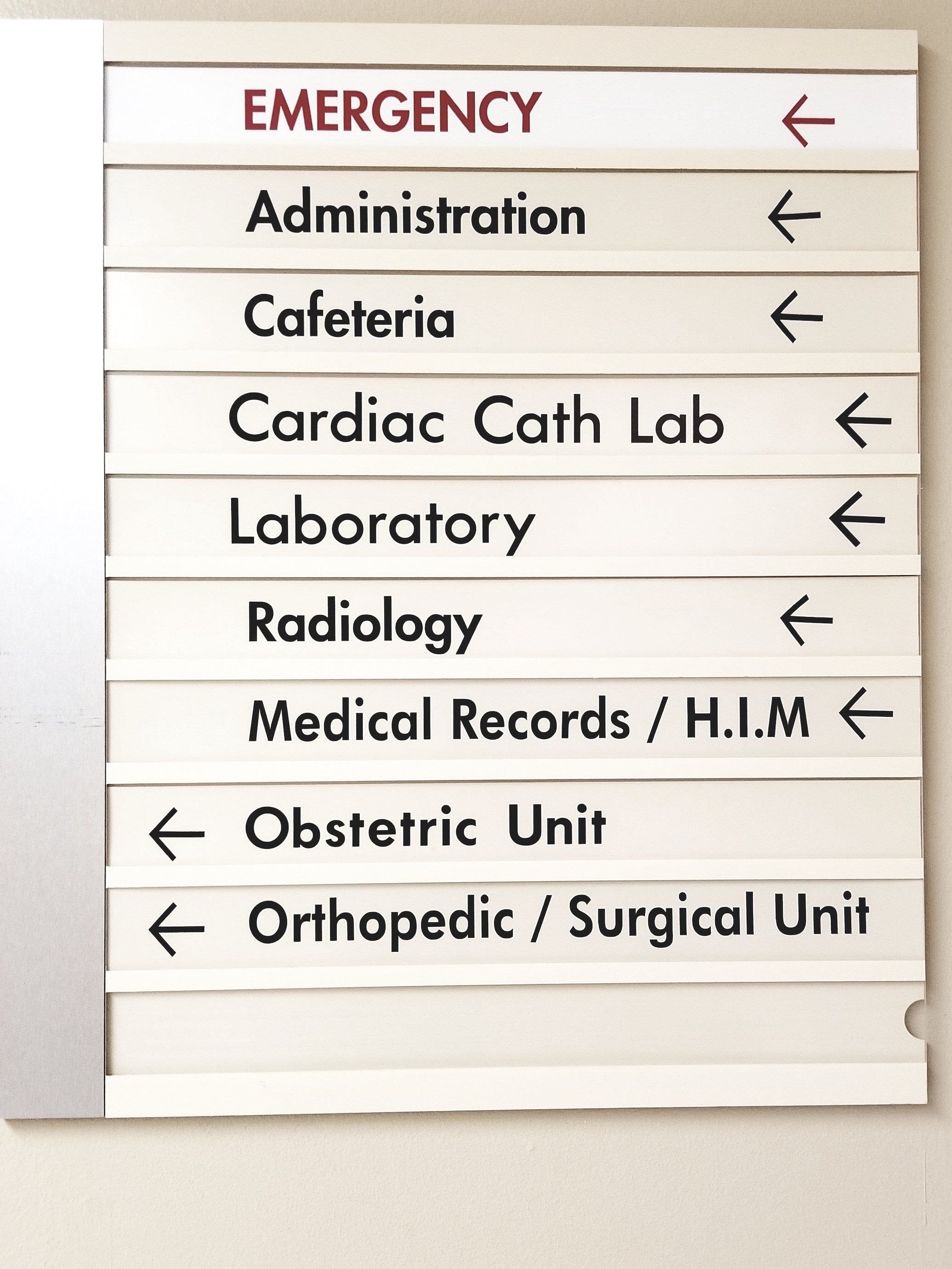 Hospital directional sign pointing left to emergency, administration, cafeteria, cardiac cath lab, laboratory, radiology, medical records/H.I.M, obstetric unit, and orthopedic/surgical unit.