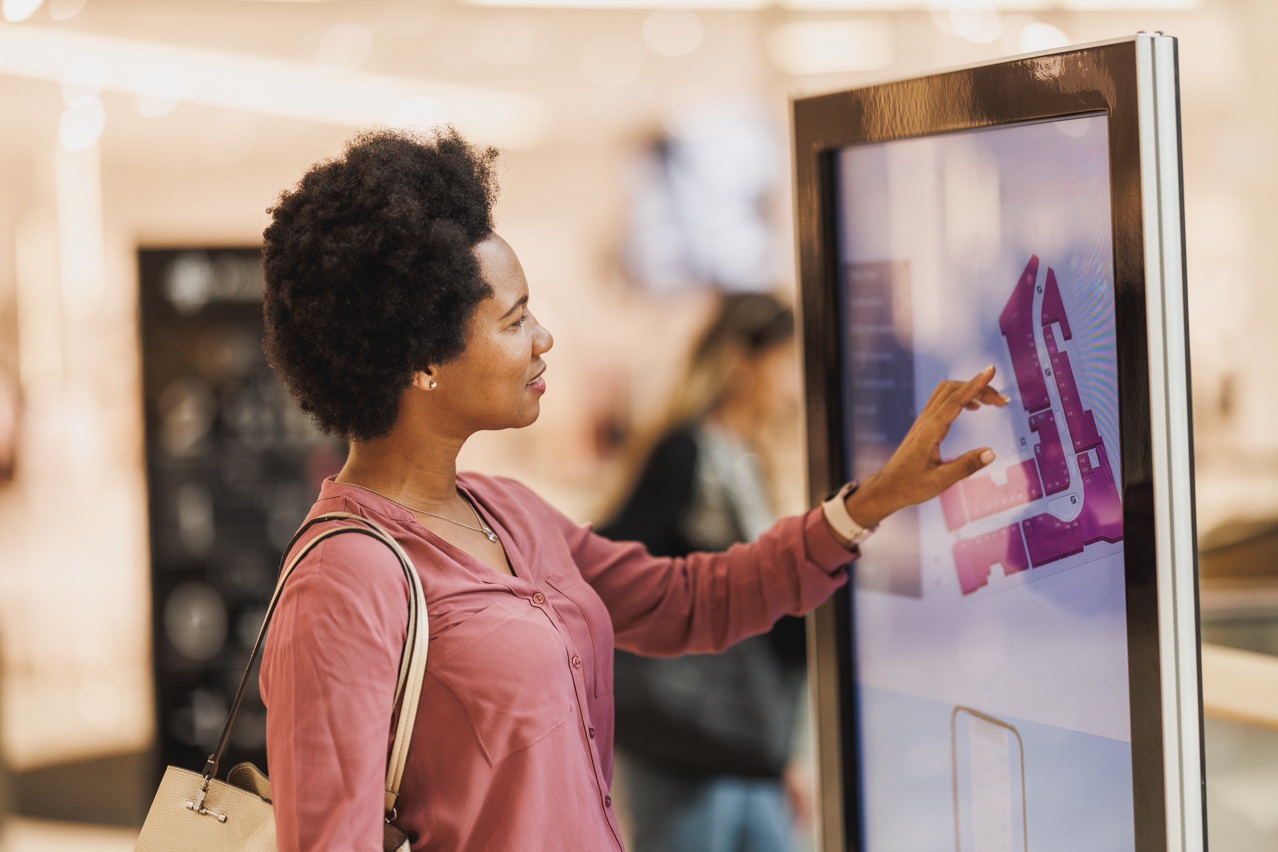 Woman using a touchscreen directory map in a shopping mall.