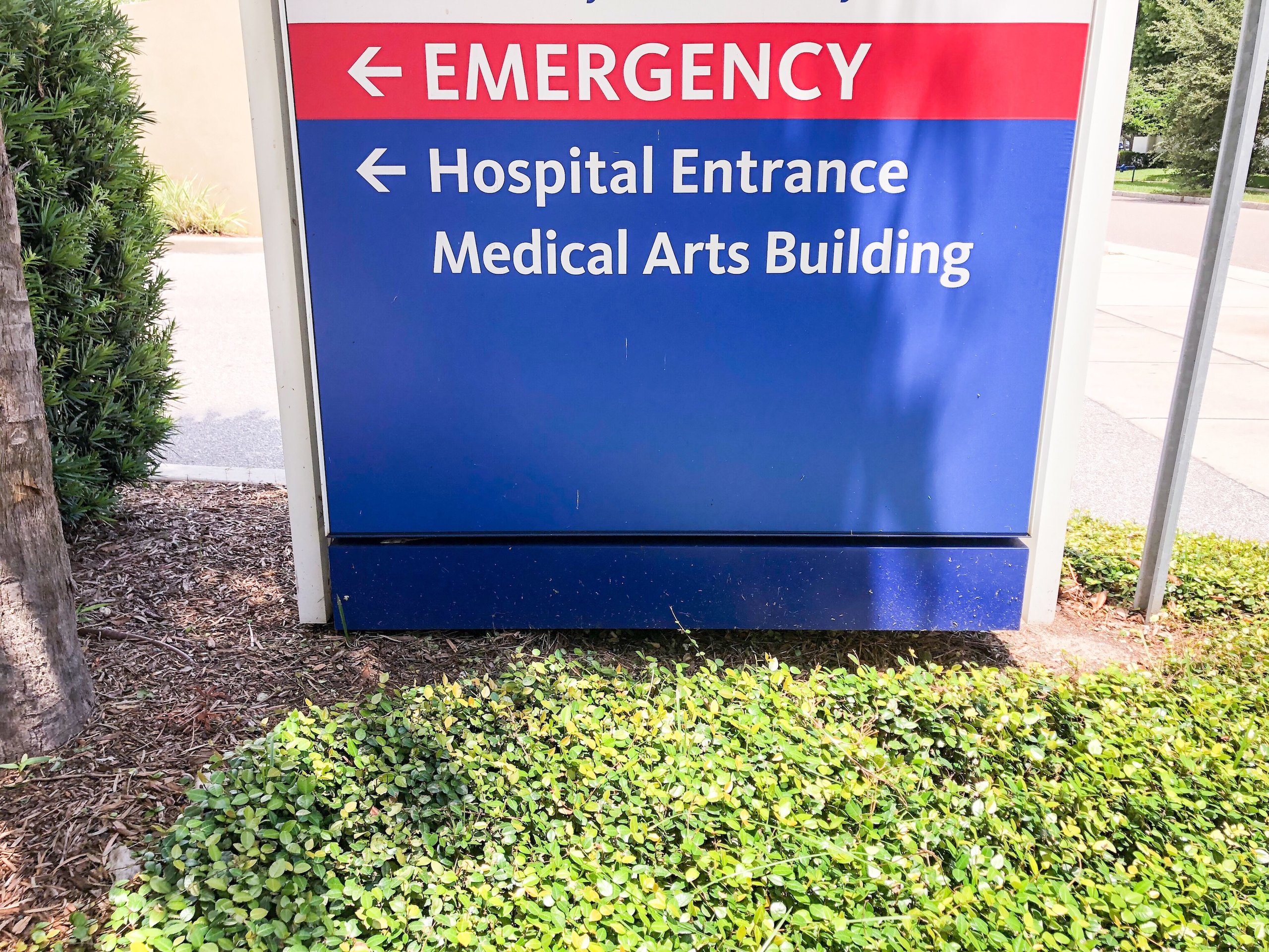 Hospital sign with directions pointing left to Emergency and Hospital Entrance Medical Arts Building.