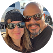 Smiling couple wearing sunglasses outdoors in a close-up selfie.