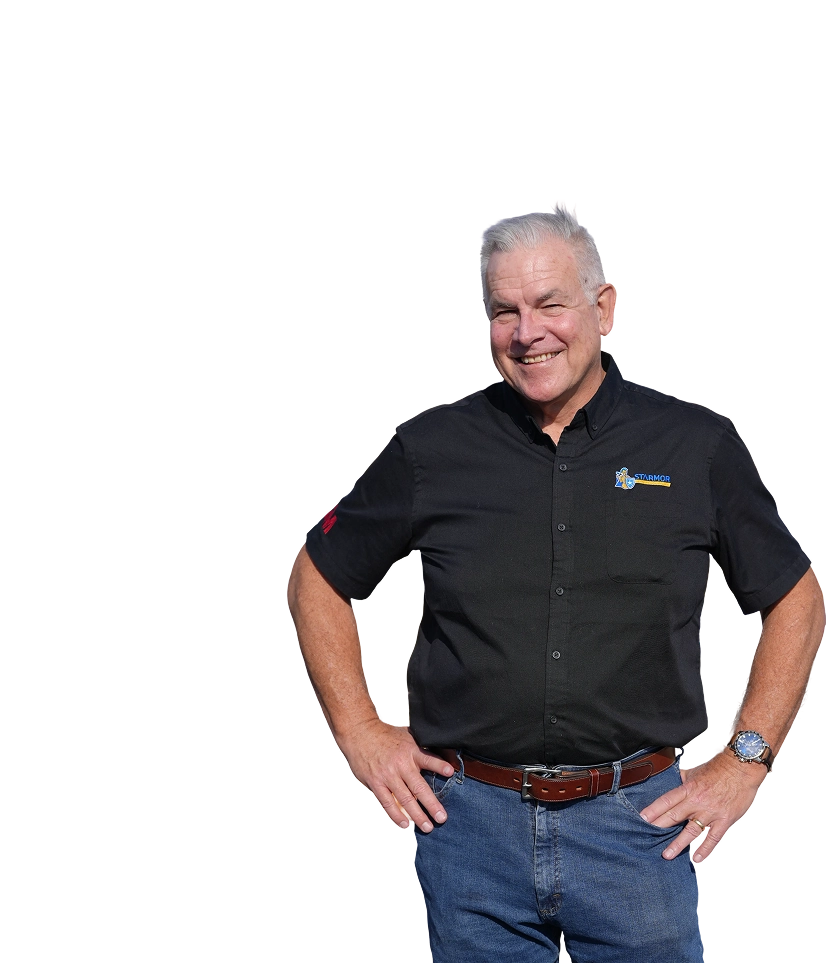 Smiling older man with gray hair wearing a black Starmor shirt and blue jeans, standing with hands on hips.