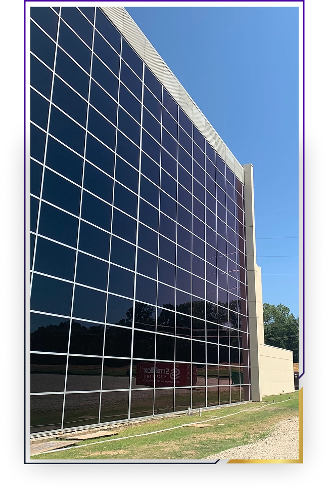 Modern building facade with large reflective glass windows under a clear blue sky.