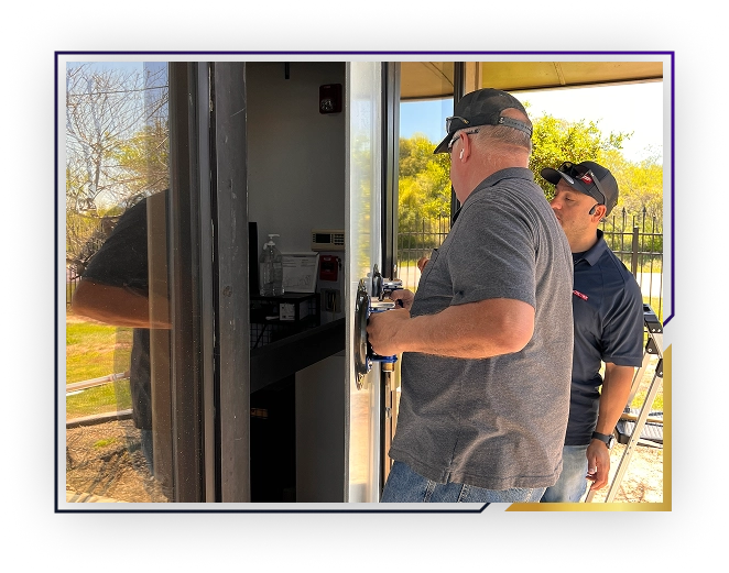 Two men installing or repairing a glass door, one holding the door with suction handles and the other watching closely.