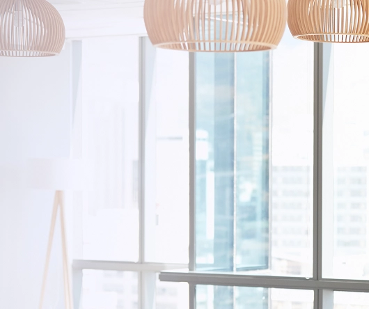Bright room with large windows overlooking a cityscape, featuring modern pendant lamps and a floor lamp.