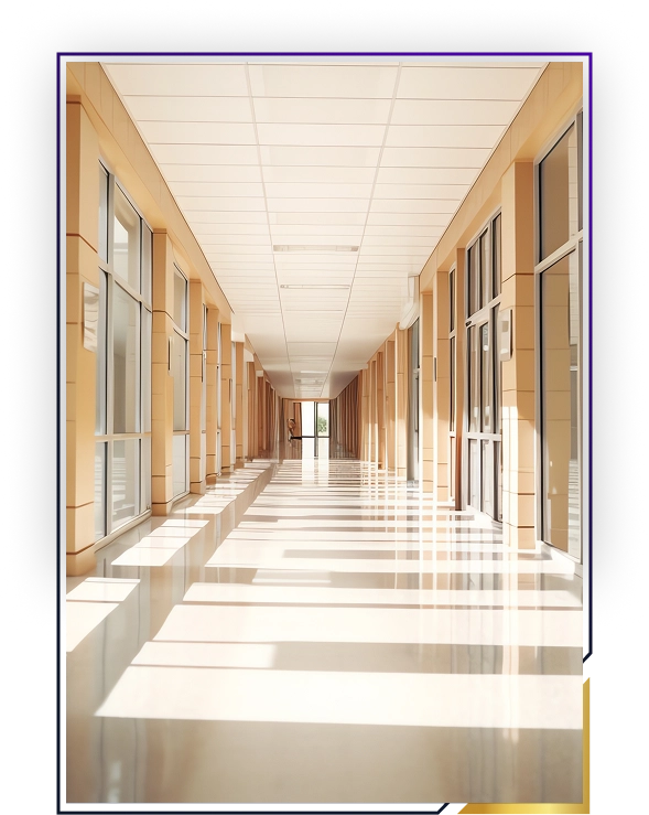 Sunlit corridor with large windows on both sides casting shadow patterns on the polished floor.