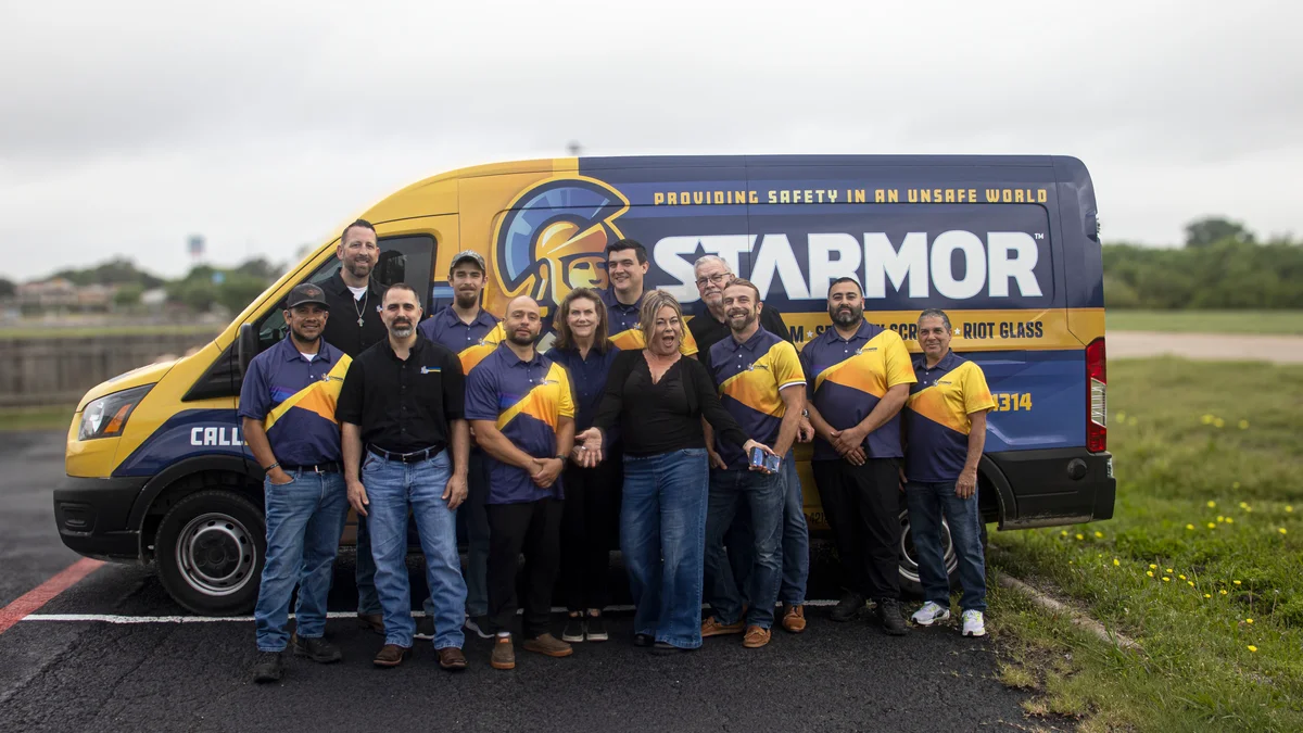 Group of 12 people standing in front of a yellow and blue Starmor company van with safety message and logo.