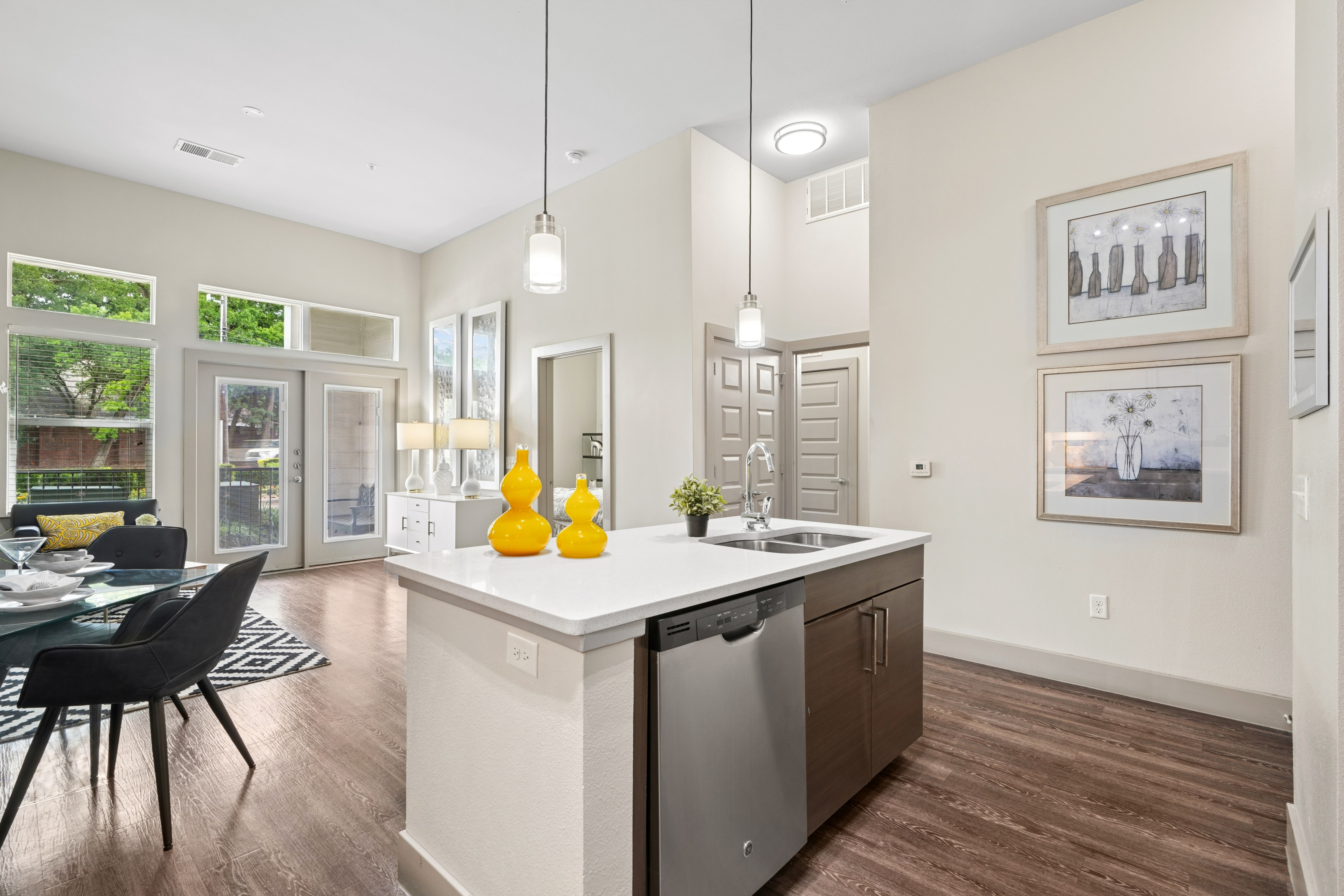 View of kitchen with stainless steel appliances and kitchen island and view into dining area, bedroom, and hallway