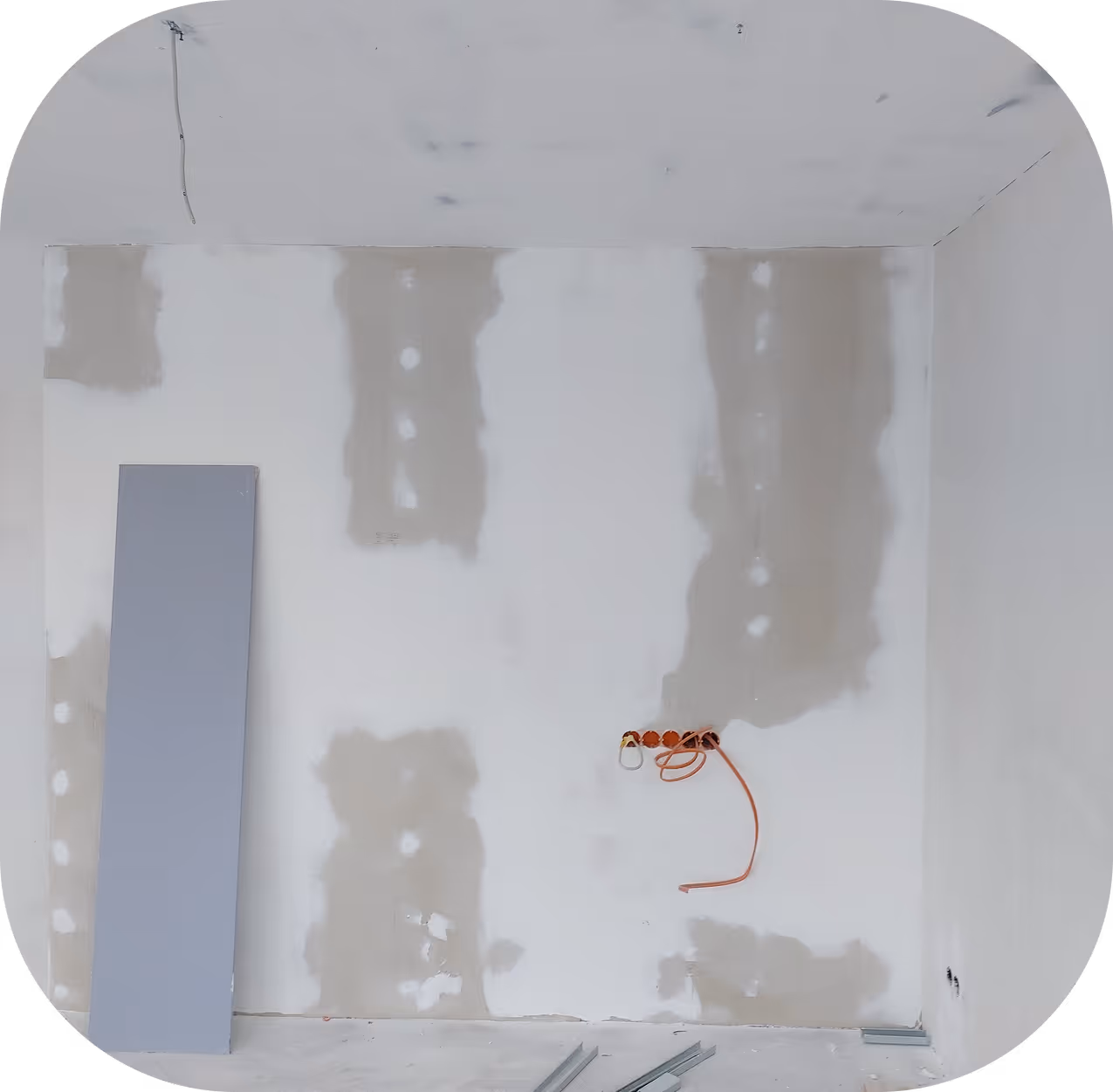 Unfertiger Raum mit Rigipsplatten an den Wänden und freiliegenden Elektrokabeln im Renovierungszustand.