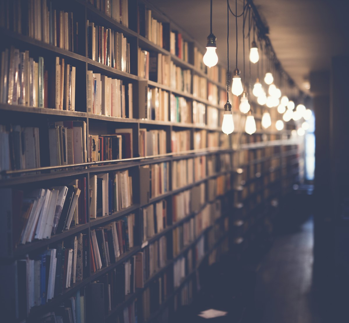 Towering library aisles stretching into the distance — the scattered knowledge Rovo Search turns into one searchable shelf. Photo from Unsplash.