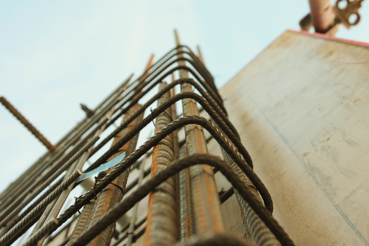 Worm's-eye view of steel reinforcing bars forming a dense structural grid, illustrating the rebuilt foundation beneath Jira's core views. Photo from Unsplash.