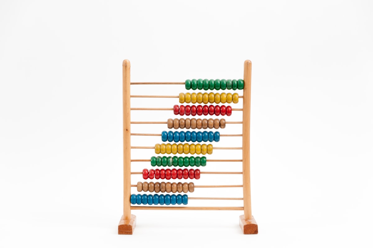 A wooden abacus with colorful beads on a white background, a nod to the era when capacity plans and budget math lived outside the work