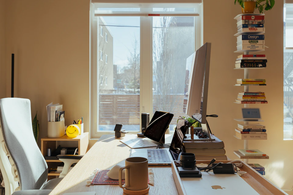 A sunlit home office desk with a computer and books