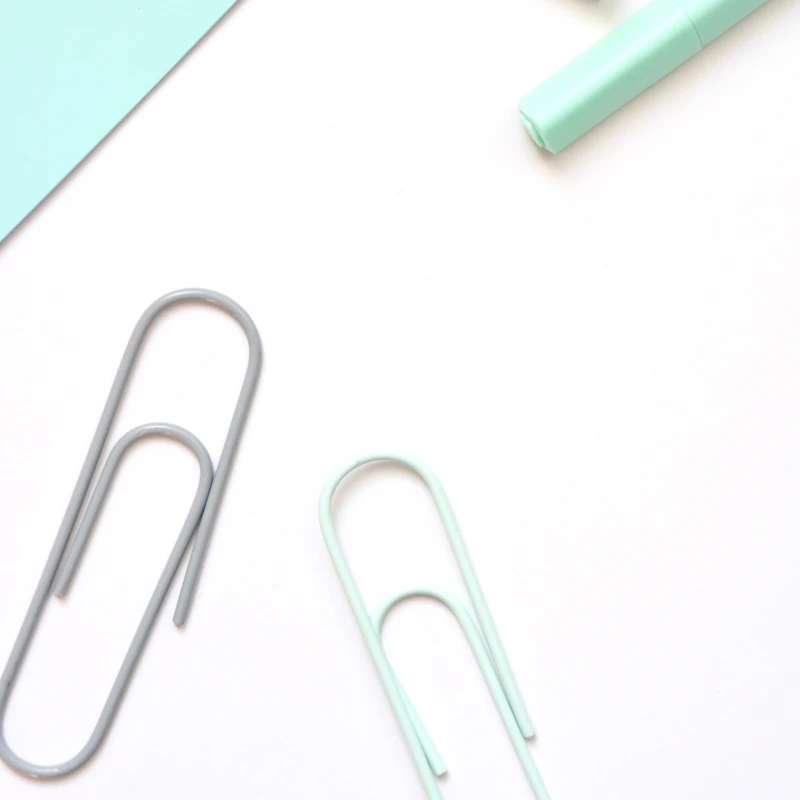 Paper clips, small clothespins and a marker on a plain background