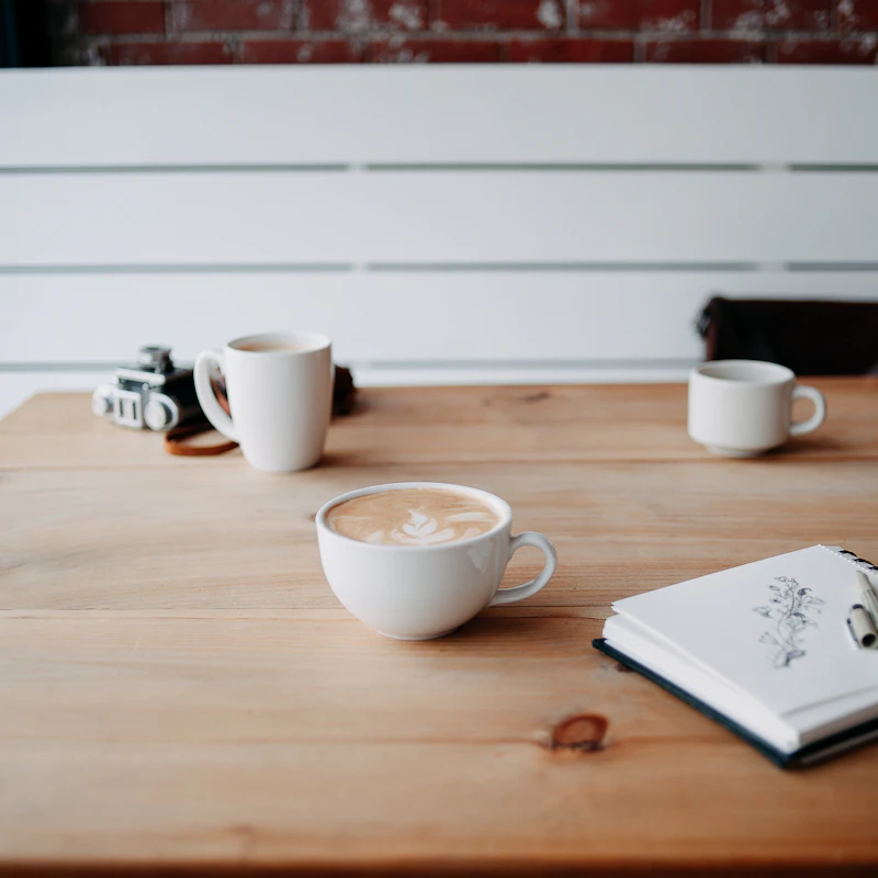 Two cups of coffee and a notebook on a wooden table