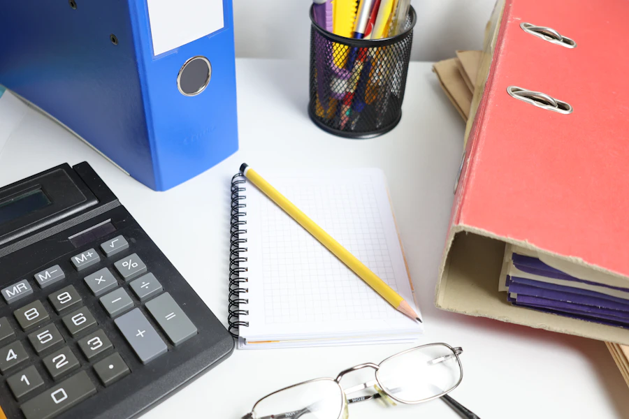 A calculator, notebook and folders arranged on a desk