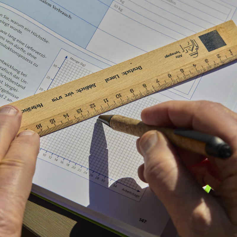 A person checking a printed graph with a ruler and pen