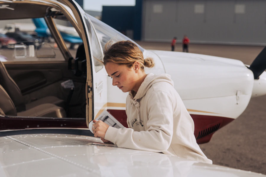 A pilot checking a preflight checklist beside a small aircraft