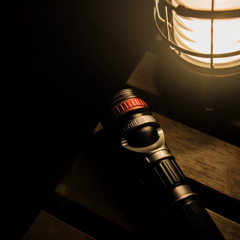 A flashlight beside a glowing camping lantern