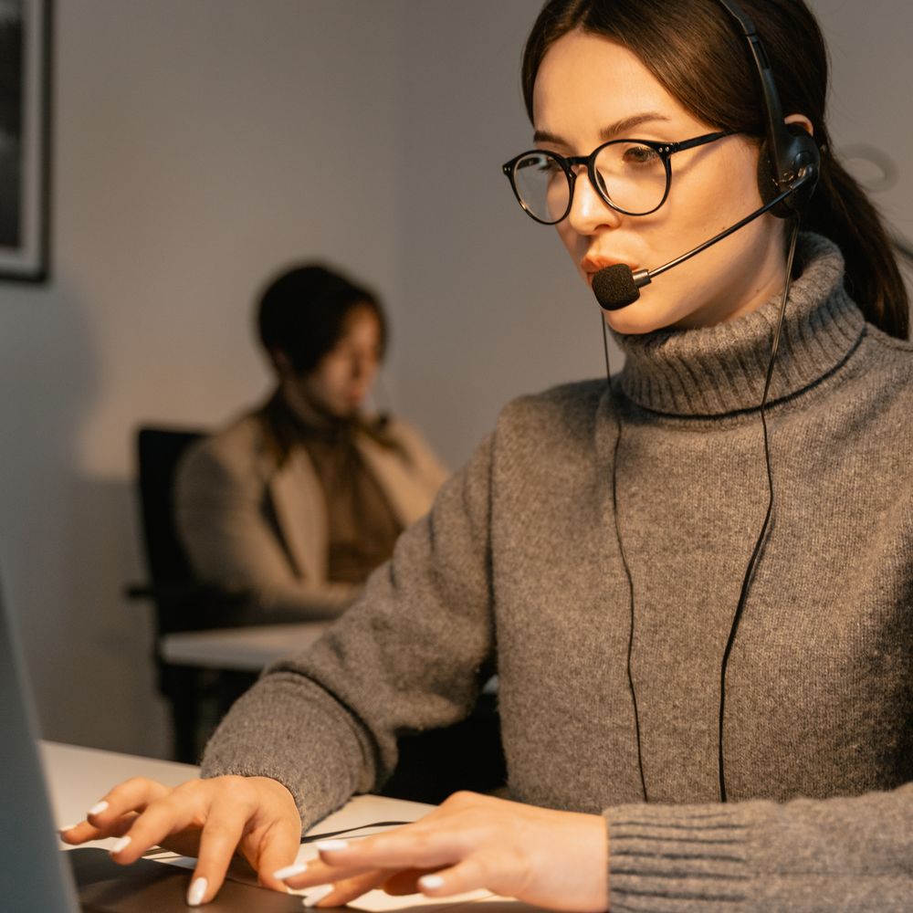 A support professional working at a computer with a headset, illustrating IT service-desk operations.