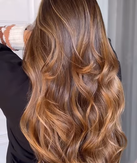 Friseurin beim Stylen von langen, gewellten Haaren