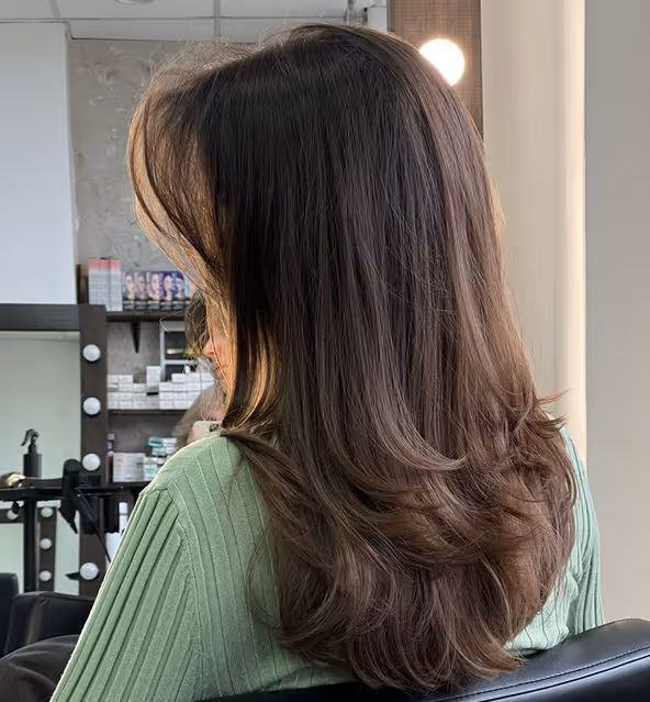 Friseurin beim Stylen von langen, gewellten Haaren