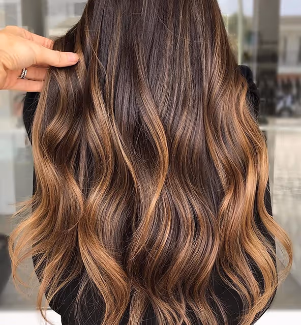 Langes, gewelltes Haar in warmem Balayage-Look von hinten