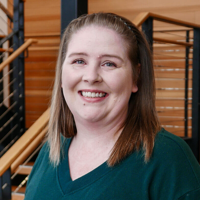 Smiling Systems Tech Consultant IT professional in green top standing in modern Billings MT office building
