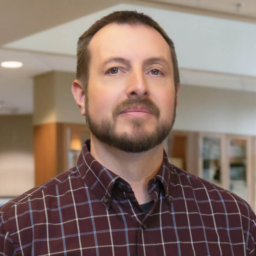Man in plaid shirt standing in modern office environment, IT professional at Billings MT managed service provider