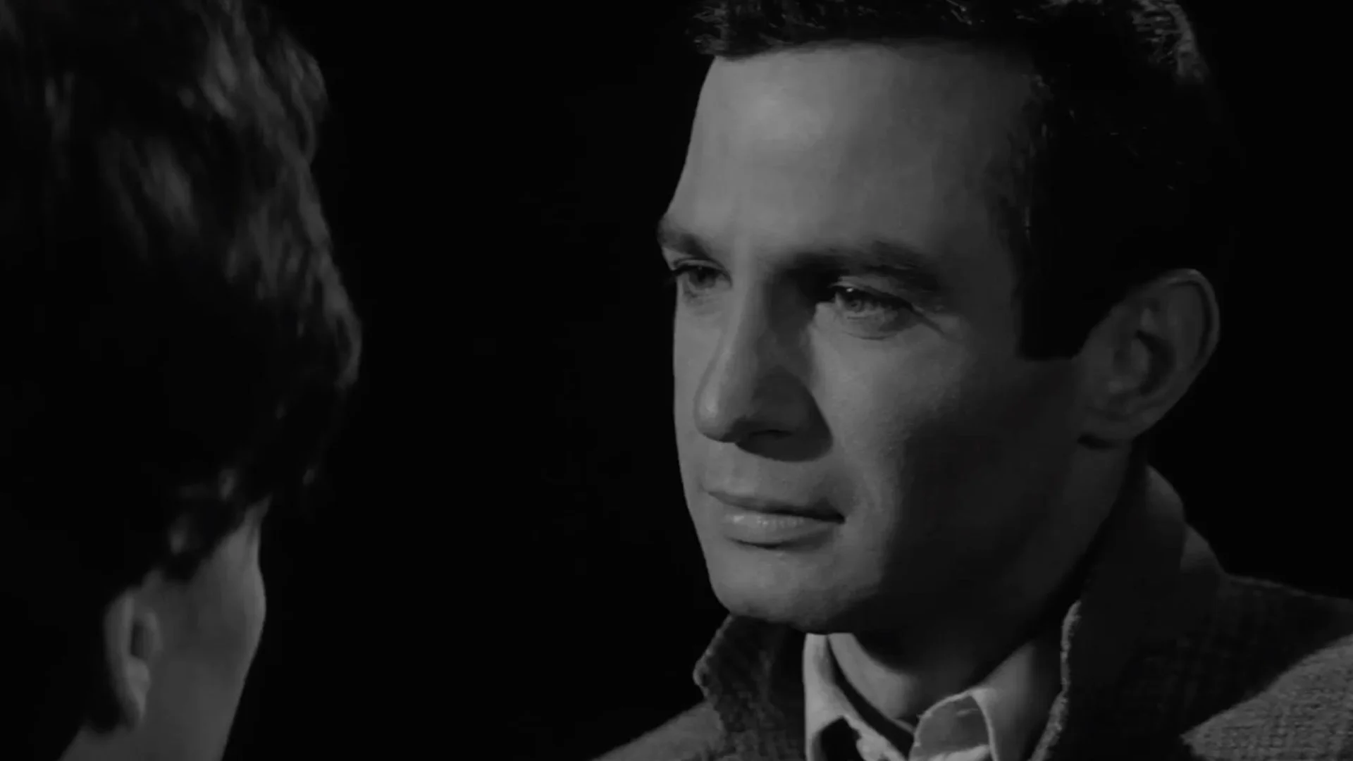 Close-up of a man looking thoughtfully at another person in a black-and-white setting.