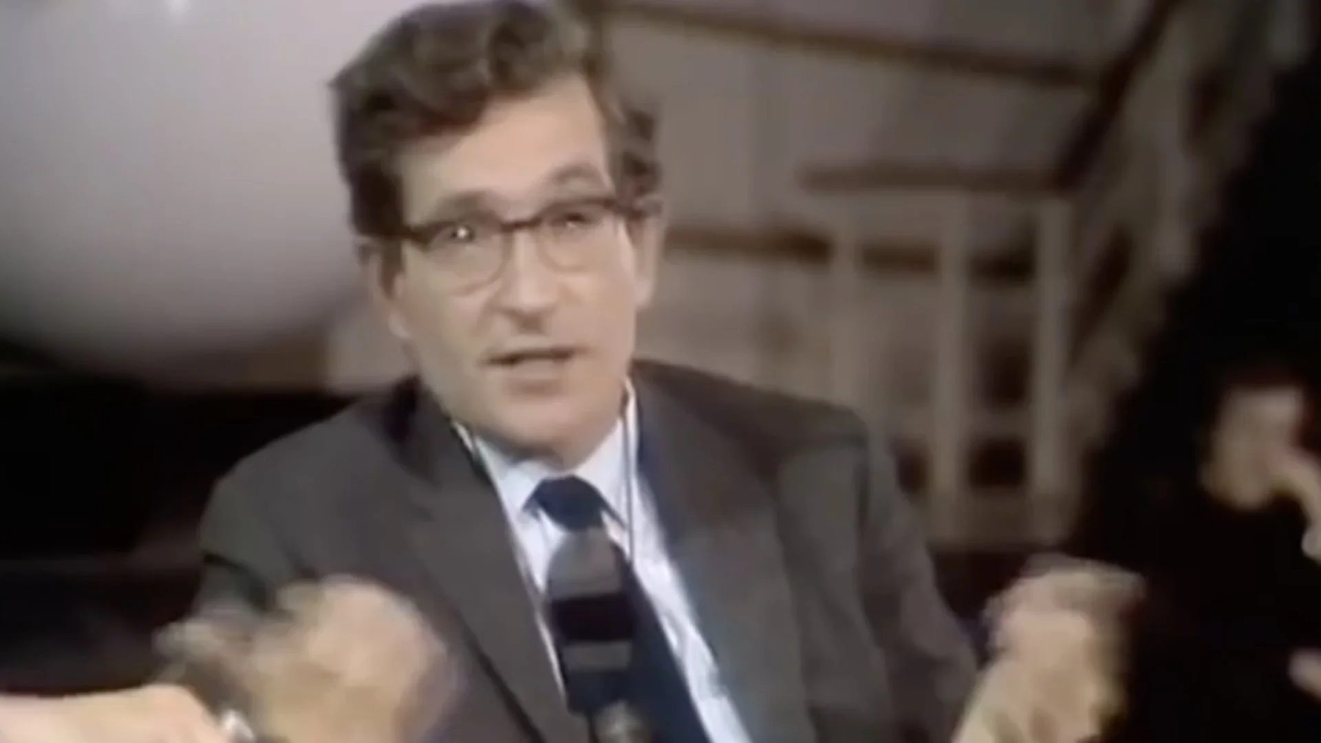 Man in glasses and suit speaking during an interview or discussion.