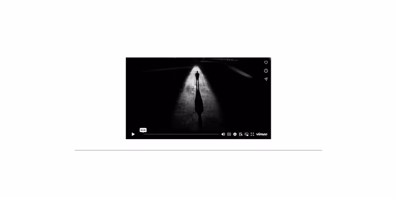 Black and white video still showing a person walking under a streetlight casting a long shadow on the ground.