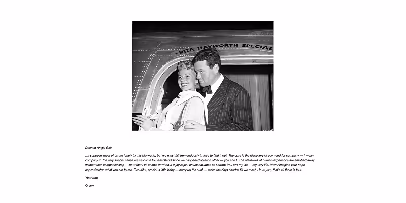 Black and white photo of a smiling woman and a man in a suit standing close together near a metallic doorway labeled 'RITA HAYWORTH SPECIAL'.