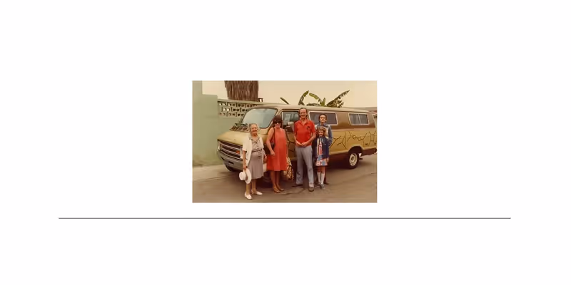 Four people standing in front of a yellow van with art on its side in an urban setting.