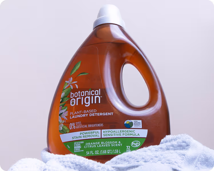 Bottle of Botanical Origin plant-based laundry detergent with orange blossom and citrus leaves scent on a white towel.